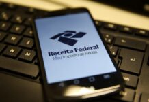 Empresas têm até esta sexta-feira, para entregar informe de rendimentos referente a 2025 Celular com logo da Receita Federal